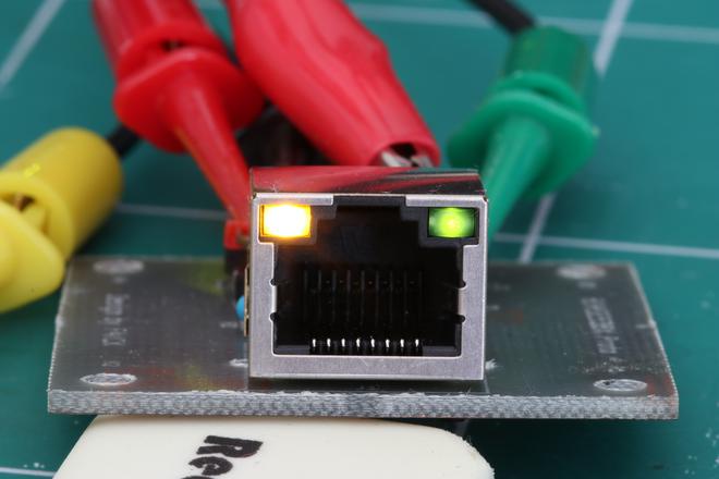 A photo of the assembled PCB from the front, the LEDs of the RJ45 port are lit.